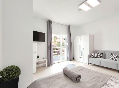 ein weißes Wohnzimmer mit einem Sofa und einem TV in der Unterkunft Fantastico 4 - a45335 in Puerto de la Cruz