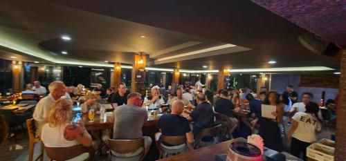 a group of people sitting at tables in a restaurant at Oceanview Bungalows by EAT in Karon Beach