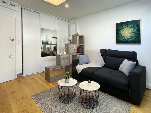 - un salon avec un canapé noir et 2 tables dans l'établissement HOMEY TINY - Chambre privée - Située en Hyper-centre - Disney Plus et Wifi inclus - Sans SDB - Proche de Genève et des transports en commun, à Annemasse