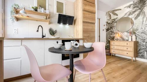 une cuisine avec une table et deux chaises roses dans l'établissement HOMEY Moorea - Hyper-centre/ Proche Genève/ wifi, à Annemasse