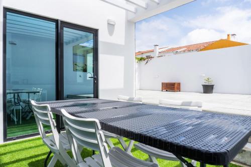 a dining room with a black table and white chairs at EnCanto Terrace House in Ponta Delgada