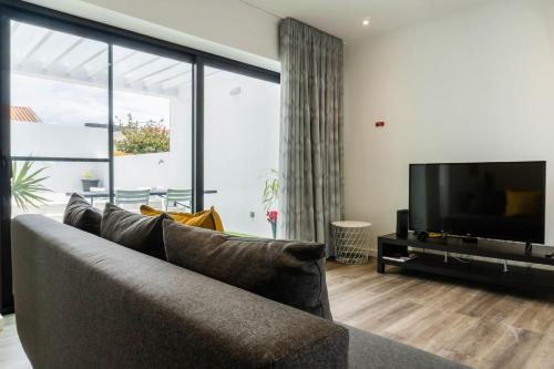a living room with a couch and a flat screen tv at EnCanto Terrace House in Ponta Delgada