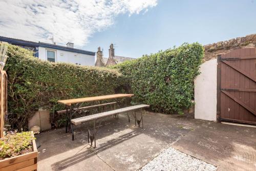 a wooden bench sitting in front of a hedge at The Loft on the Lane - Crail in Crail