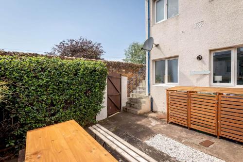a house with a fence and a wooden bench in front of a hedge at The Loft on the Lane - Crail in Crail