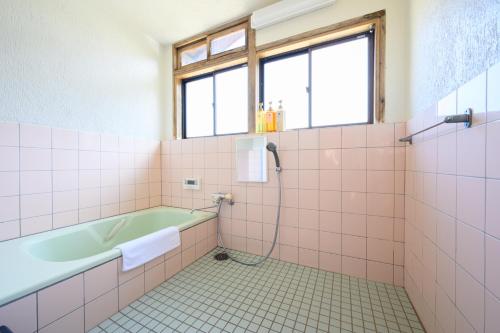 a bathroom with a tub and pink tiles at 玉造和暖 WaDan 島根県玉造温泉街に佇む和の趣あふれる古民家旅館 supported by COCOSTAY in Matsue