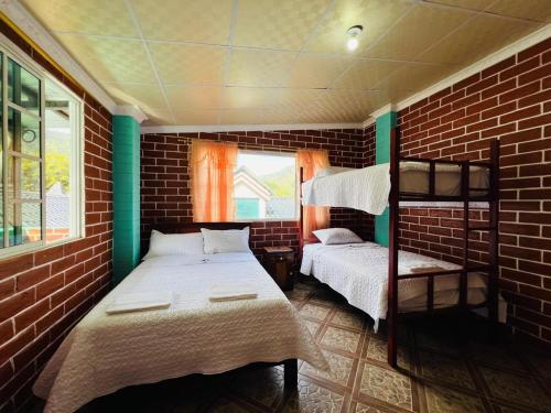 a bedroom with two bunk beds and a brick wall at Comfort en Attic Apartment in Baños