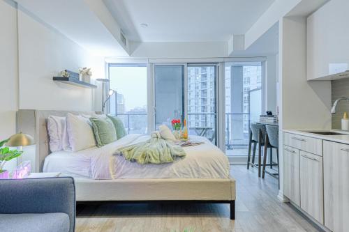 a bedroom with a bed and a kitchen with a balcony at RivetStays - The Jarvis in Toronto