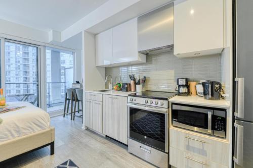 a kitchen with a stove top oven next to a bed at RivetStays - The Jarvis in Toronto