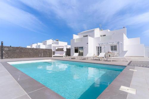 a villa with a swimming pool in front of a house at Vv Villa Secretos de Yaiza 2 by HH - private pool in Yaiza