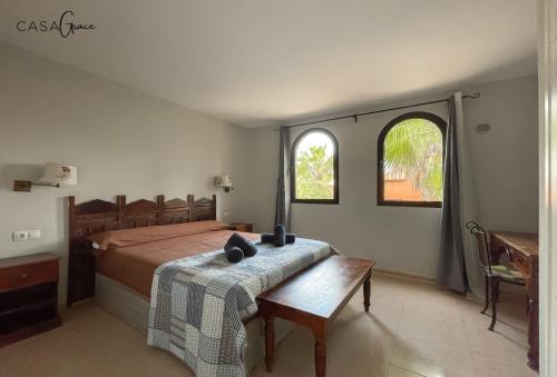 sypialnia z łóżkiem ze stołem i 2 oknami w obiekcie Rentalfue Tamarindo 1 casa Grace w Corralejo