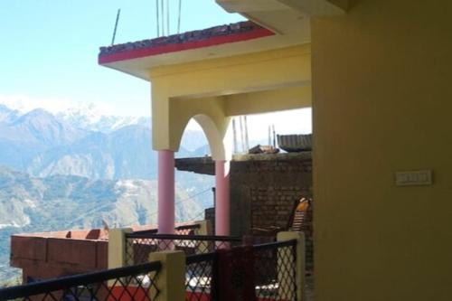 a building with a balcony with a view of mountains at StayApart Mount Kailash Guest House in Munsyari