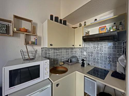 Il comprend une petite cuisine équipée d'un four micro-ondes et d'un comptoir. dans l'établissement Appartement lumineux avec mezzanine, terrasse et coin cabine - FR-1-475-180, à Saintes-Maries-de-la-Mer