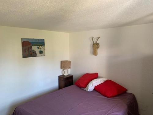 une chambre avec un lit avec deux oreillers rouges dans l'établissement Maison 8 pers, jardin privatif, climatisation, animaux admis - FR-1-475-185, à Saintes-Maries-de-la-Mer