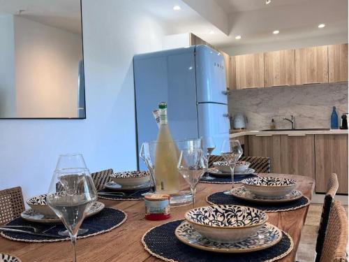 - une table en bois avec des assiettes, des verres et une bouteille dans l'établissement Maison neuve élégante pour 6 pers. avec climatisation, proche du centre de Saintes-Maries-de-la-Mer - FR-1-475-187, à Saintes-Maries-de-la-Mer