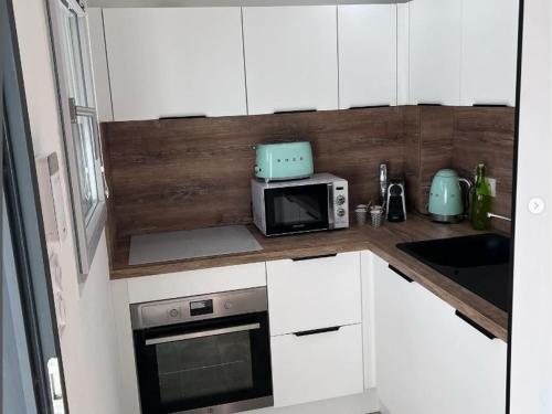 une cuisine avec des armoires blanches et un micro-ondes dans l'établissement Charmante maison neuve à Saintes-Maries-de-la-Mer pour 4 personnes - FR-1-475-189, à Saintes-Maries-de-la-Mer