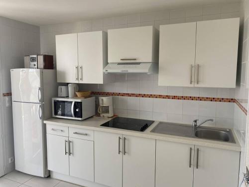une cuisine avec des armoires blanches et un réfrigérateur blanc dans l'établissement T2 2* avec Terrasse & Jardinet - 400m Plage - FR-1-738-45, à Saint-Palais-sur-Mer