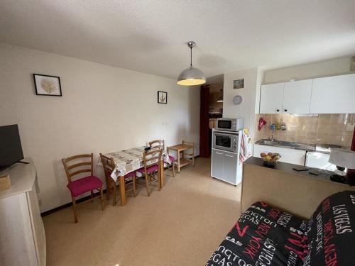 une cuisine et un salon avec une table et des chaises dans l'établissement Coquet studio avec terrasse au Lioran, animaux admis - FR-1-787-119, à Laveissière