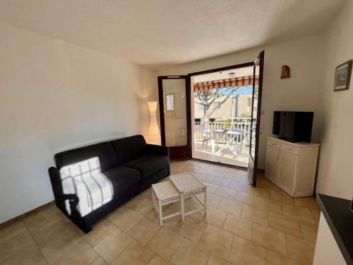 un salon avec un canapé noir et une télévision dans l'établissement Studio climatisé avec parking face à la mer - 2 couchages - FR-1-226B-233, à Cavalaire-sur-Mer