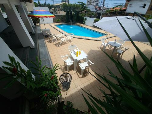 a patio with a table and an umbrella and a pool at Mansão Casa Mais in Aracaju