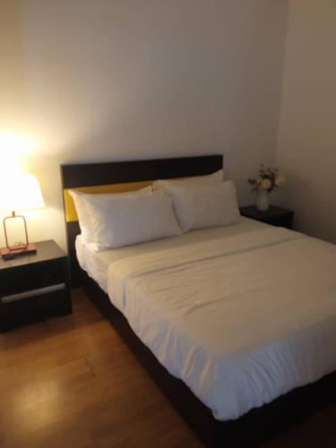 a bedroom with a large bed with white sheets and a lamp at Luxury Homestay Rooms with Balcony in Kuala Lumpur