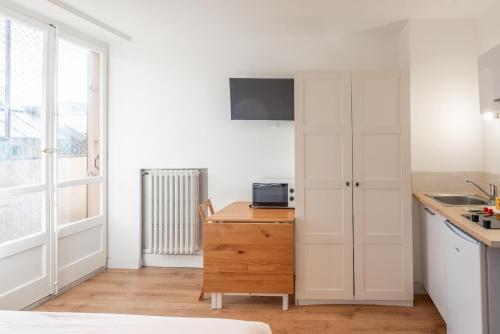 une cuisine avec des placards blancs et un bureau avec un four micro-ondes dans l'établissement M22 studio avec balcon proche de la gare, à Annemasse