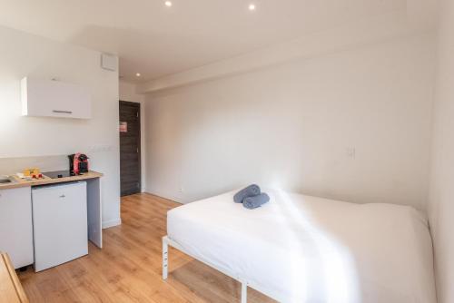 Cet appartement comprend une chambre avec un lit blanc et une cuisine. dans l'établissement M22 studio avec balcon proche de la gare, à Annemasse
