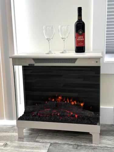 a bottle of wine and two wine glasses sitting on a fireplace at Colindale Beach Villas -- MIni Villas in Port Hood