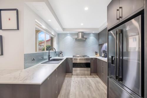 a kitchen with gray cabinets and a sink and a refrigerator at Makai - Hawaiian for "toward the ocean" in Yaroomba