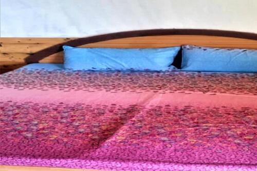 a bed with a pink and purple blanket and blue pillows at Galaxy Inn by StayApart in Kūfrī