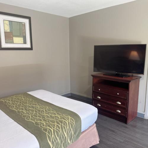 a hotel room with a bed and a flat screen tv at Deluxe inn in Bossier City