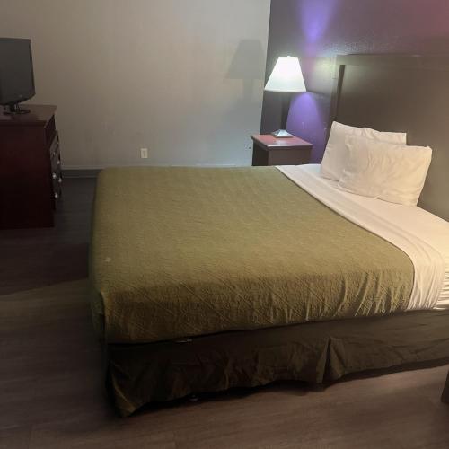 a hotel room with a large bed with a green blanket at Deluxe inn in Bossier City