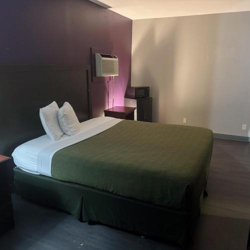 a hotel room with a large bed with a green blanket at Deluxe inn in Bossier City