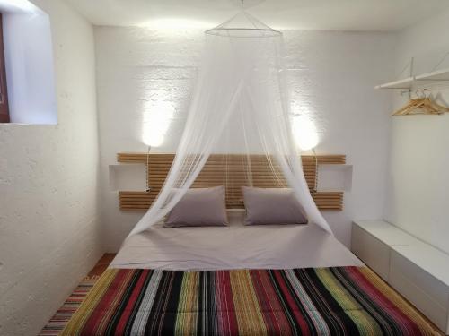 a bed with a mosquito net in a room at BeGuest Casas de Taipa in Lagoa