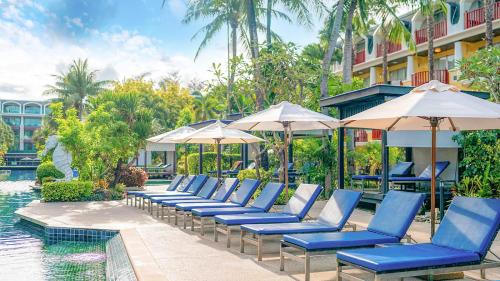 eine Reihe blauer Stühle und Sonnenschirme neben einem Pool in der Unterkunft Phuket Graceland Resort and Spa in Patong Beach