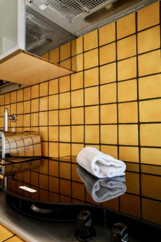 a yellow tiled bathroom with a sink and towels at Casa LORY in Varazze