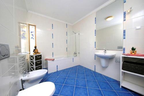 a bathroom with blue tiled floors and a tub and sink at Apartment Karin, Town Centre in Tavira