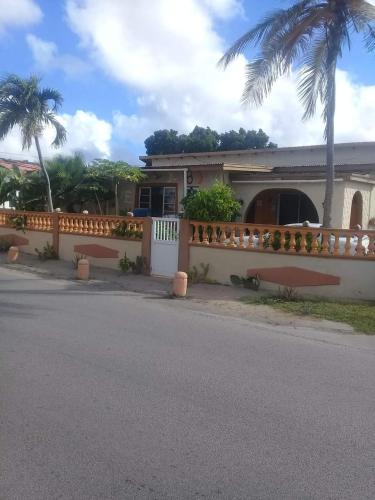 a house with a fence and a palm tree at Backpack Cabin A 49149 in Oranjestad