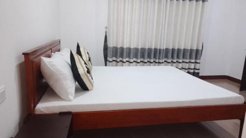 a bed with white sheets and pillows in a room at King Elephant, Homestay Pinnawala in Rambukkana