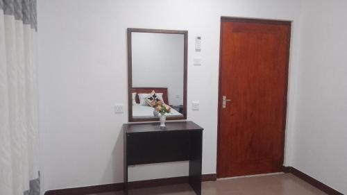 a room with a mirror and a table with a vase of flowers at King Elephant, Homestay Pinnawala in Rambukkana