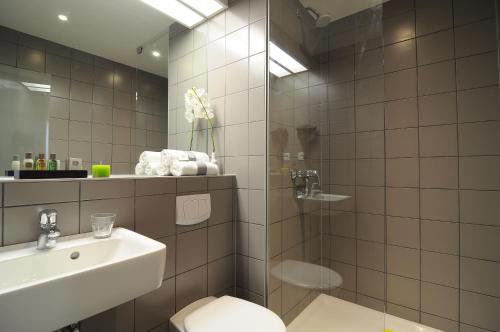 y baño con ducha, aseo y lavamanos. en BEST WESTERN Hotel Brussels South en Ruisbroek