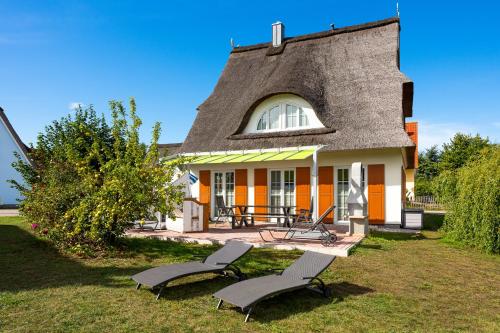 a house with a thatched roof with two chairs in front at C 4 Reethaus ELSA mit Außenwhirlpool und Sauna in Gramkow