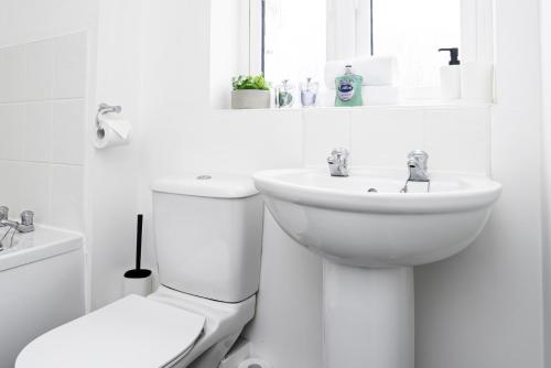 Un baño blanco con inodoro y lavabo. en K Suites - Shetland Court, en Bridgwater