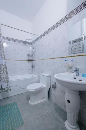 a bathroom with a toilet and a sink and a tub at Yodgorlik Hotel in Margilan