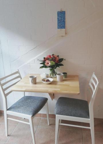 a wooden table with two chairs and a vase of flowers at Familienzeit - aktuell noch freie Kapazitäten im Sommer! in Riepsdorf