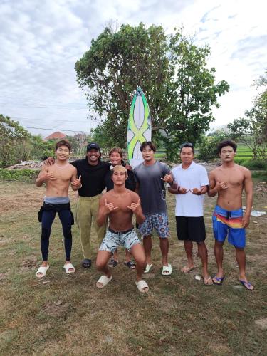 a group of men posing for a picture with a surfboard at Middle rooms surfhomestay in Airsatang