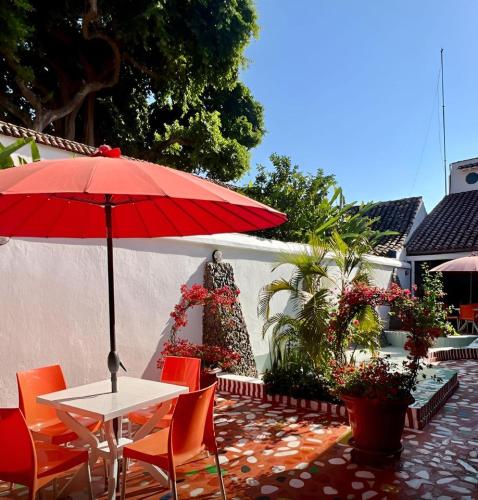 una mesa y sillas con una sombrilla roja en el patio en Hotel Casa De España, en Mompox