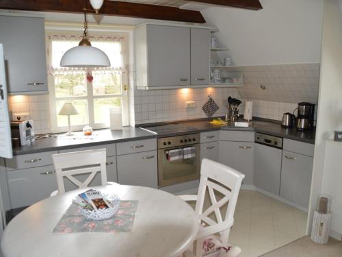 a kitchen with a table and two chairs and a kitchen with white cabinets at Haus Bornholm Whg Anemone in Nieblum