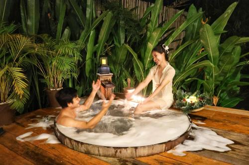 a man and a woman sitting in a hot tub at บ้านไร่มีสุข Baanrai Meesuk in Surat Thani