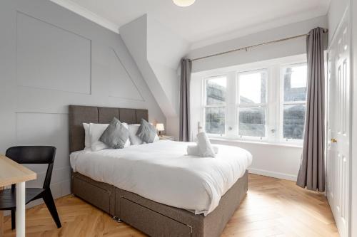 a bedroom with a bed and a desk and windows at Spire View Apartment in St. Andrews