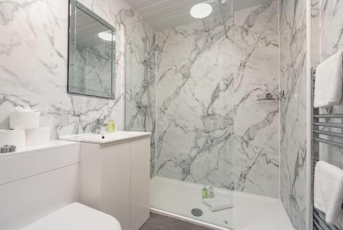 a white bathroom with a marble wall at Spire View Apartment in St. Andrews